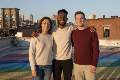 Three diverse friends embracing on a Brooklyn rooftop at sunset - inclusive dating for all genders and orientations article cover